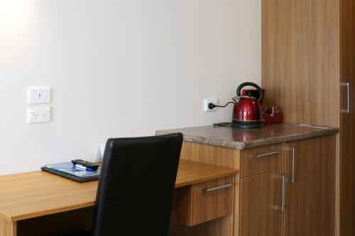a tea kettle sitting on top of a wooden desk at The Victoria Hotel Dunedin in Dunedin