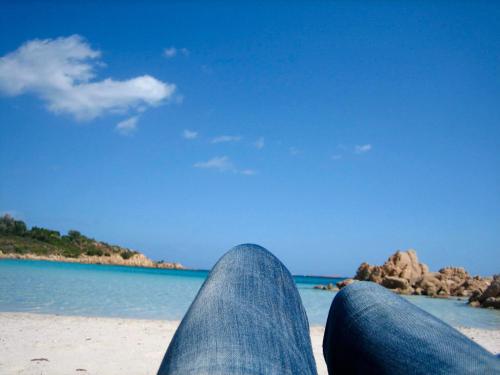 a person sitting on the beach with their legs up at Apartment Valentina in Tergu