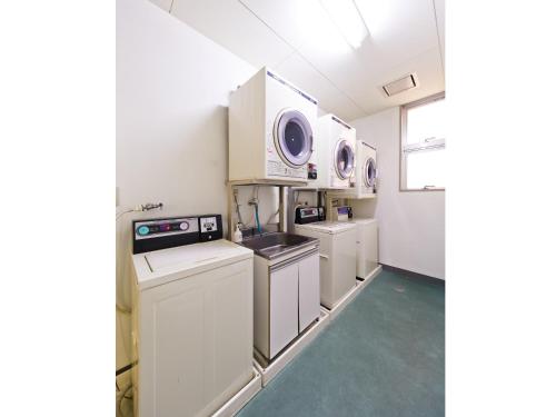 a kitchen with white cabinets and a washer and dryer at Koga Central Hotel in Koga