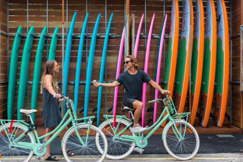 a woman standing next to two bikes in front of surfboards at Wake Up! Byron Bay in Byron Bay
