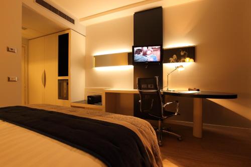 a bedroom with a bed and a desk and a tv at Holiday Inn Milan Nord Zara by IHG in Cinisello Balsamo