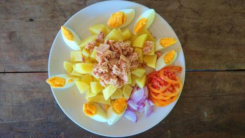 a white plate of food on a wooden table at Forra Dive Resort Sunrise in Ko Lipe