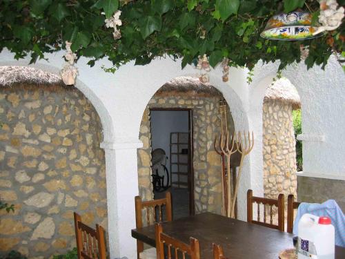 a dining room with a table and a stone wall at Finca Malyma with 2 villas and 1 apartment, beach front 10,000m2 botanic garden in Zahora