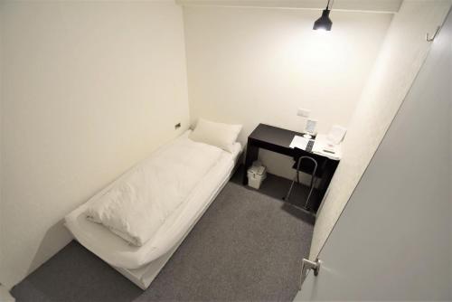 a small white room with a bed and a desk at Inn Cube - Taipei Main Station in Taipei