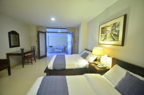 a hotel room with two beds and a desk at Metro Vigan Inn in Vigan