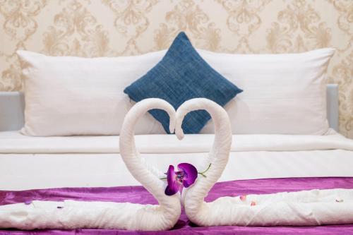 two swans shaped like hearts sitting on a bed at White Residence Hotel & Apartment in Phnom Penh