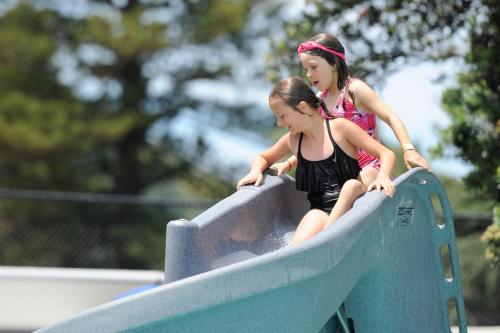 two little girls on a slide at a playground at Waikanae Beach TOP 10 Holiday Park in Gisborne