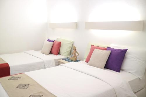 three beds with colorful pillows in a room at Villa Babeh in Bandung