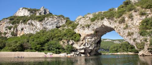 an arch in the water in front of a mountain at Cairenou Location in Saint-Martin-dʼArdèche