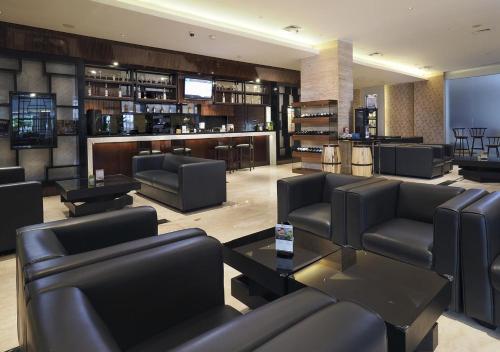 a waiting room with couches and tables and a bar at Grand Mercure Solo Baru in Solo