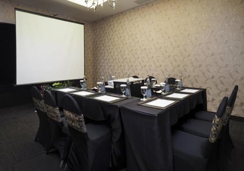 a conference room with a table with chairs and a screen at Grand Mercure Solo Baru in Solo