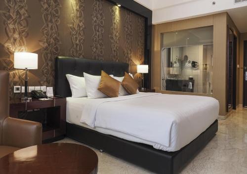 a bedroom with a large white bed and a table at Grand Mercure Solo Baru in Solo