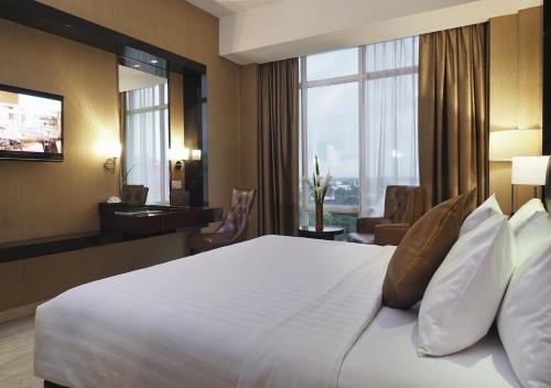 a hotel room with a large bed and a large window at Grand Mercure Solo Baru in Solo