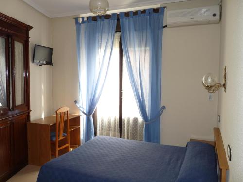sypialnia z niebieskim łóżkiem i oknem w obiekcie Hostal Fernandez w Madrycie