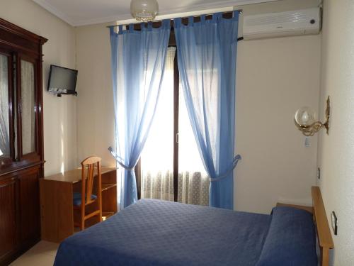 Un dormitorio con una cama azul y una ventana en Hostal Fernandez, en Madrid