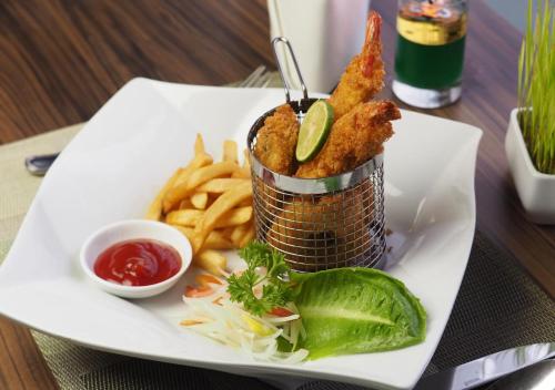 a plate of food with fried fish and french fries at Grand Mercure Solo Baru in Solo