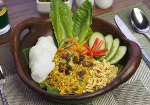 a bowl of food with rice and vegetables on a table at Grand Mercure Solo Baru in Solo