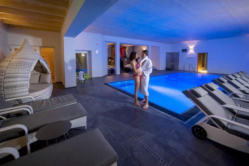 a man and a woman standing next to a swimming pool at Thula Wellnesshotel Bayerischer Wald in Lalling