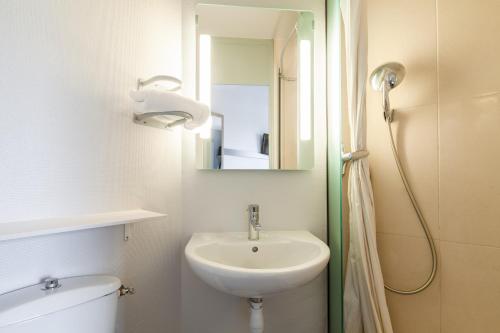 a bathroom with a sink and a toilet and a mirror at B&B HOTEL Evry Lisses 1 in Lisses