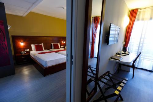 a bedroom with a bed and a table and a desk at Tulip Inn Sainte Clotilde, La Réunion in Saint-Denis