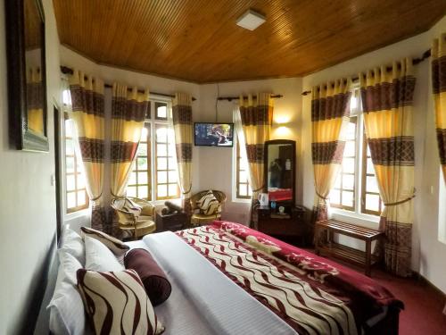 a bedroom with a large bed in a room with windows at Nuwara Eliya Hills Rest in Nuwara Eliya