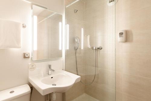 a white bathroom with a sink and a shower at B&B HOTEL La Queue En Brie in La Queue-en-Brie