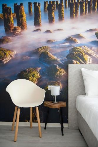 a bedroom with a bed and a white chair at City2Beach Hotel in Vlissingen