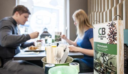 a man and woman sitting at a table eating food at City2Beach Hotel in Vlissingen