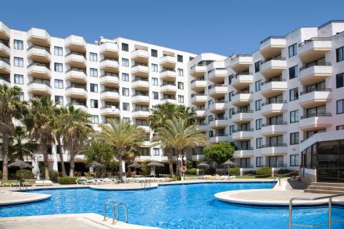 a large apartment building with a swimming pool and palm trees at TRH Jardín Del Mar in Santa Ponsa