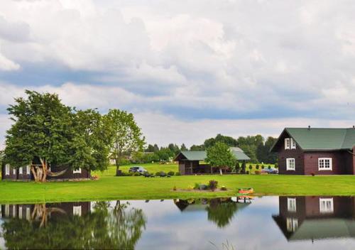 uma casa ao lado de um lago com uma casa em Sodyba Puodžių Kaimas em Mackėnai