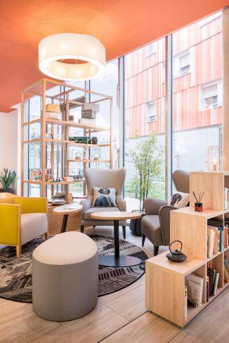 a lobby with chairs and tables and a large window at Aparthotel Adagio Access Paris Massy Gare in Massy