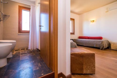 a bathroom with a toilet and a bed in a room at B&B Le Dune - Self Check in in Lascari