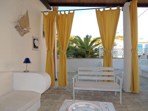 Lido Conchigliaにあるcasa con terrazzo in stile mediterraneoのベッドルーム1室(黄色いカーテン、ベッド1台、ソファ付)