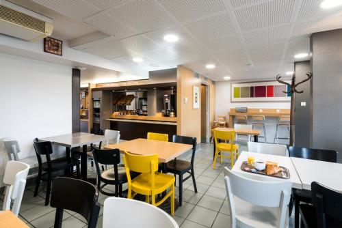 a dining room with tables and yellow chairs at B&B HOTEL Nantes Parc Expos La Chapelle in La Chapelle-sur-Erdre