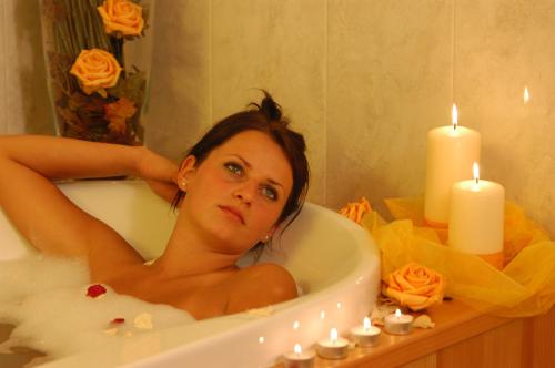 a woman laying in a bath tub with candles at Hotel Ortler in Ultimo