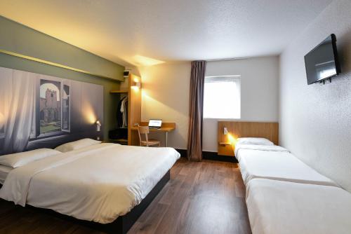 a hotel room with two beds and a television at B&B HOTEL Narbonne 1 in Narbonne
