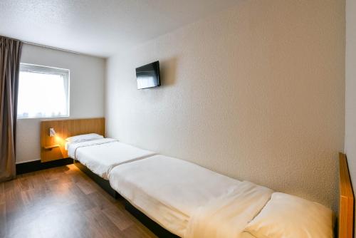 a room with two beds and a window at B&B HOTEL Narbonne 1 in Narbonne