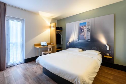 a bedroom with a bed and a desk and a window at B&B HOTEL Narbonne 1 in Narbonne