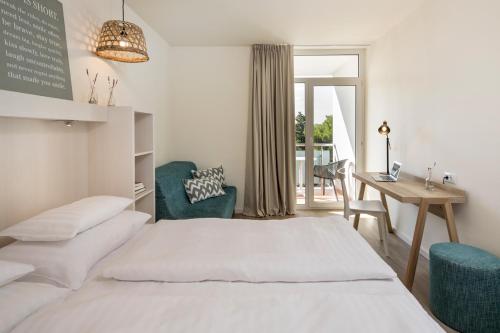 a bedroom with a bed and a desk and a table at Falkensteiner Hotel Park Punat in Punat