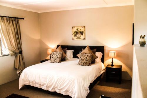 a bedroom with a bed with white sheets and pillows at Gerald's Gift Guest House in Addo