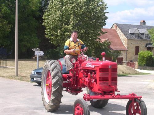 a man riding on the back of a red tractor at Hôtel Chastrusse in Nadaillac-de-Rouge