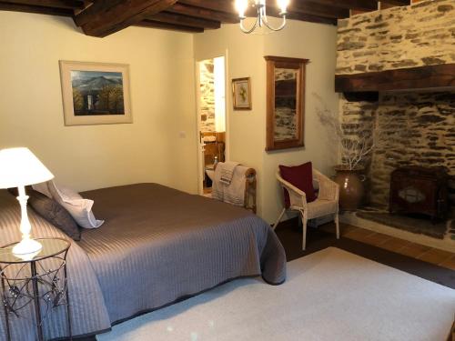 a bedroom with a bed and a stone fireplace at Les Rivieres in Caumont-sur-Orne