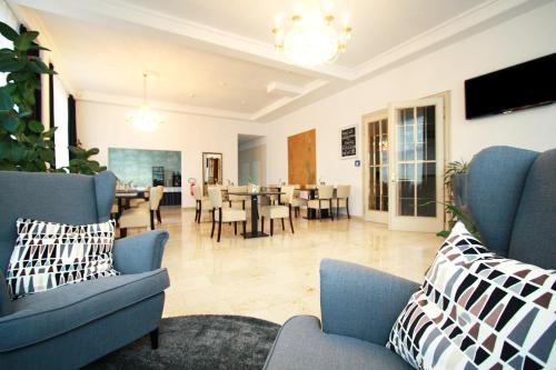 a living room with blue chairs and a dining room at Novitel Hotel Kirchheim - München Messe in Kirchheim