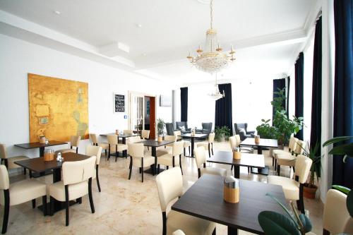 ein Restaurant mit Tischen, Stühlen und einem Kronleuchter in der Unterkunft Novitel Hotel Kirchheim - München Messe in Kirchheim