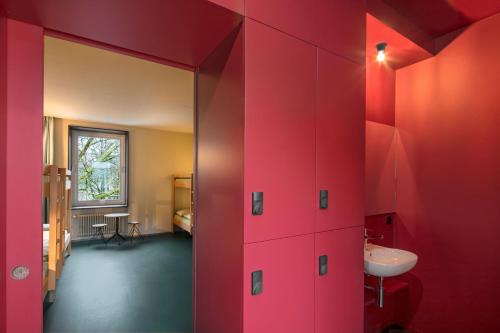 uma casa de banho com paredes vermelhas e um lavatório em Bern Youth Hostel em Berna
