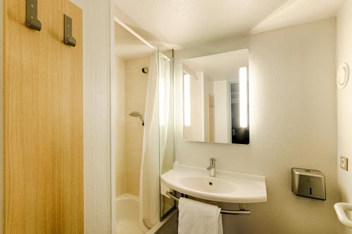 a white bathroom with a sink and a shower at B&B HOTEL Rouen Parc des Expos Zénith in Le Grand-Quevilly