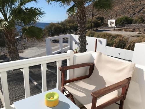 a chair on a balcony with a view of the ocean at Oklacà Patmos Beach Rooms in Patmos