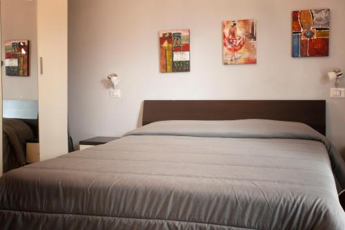 a bed in a bedroom with paintings on the wall at Asaro Camere in Campobello di Licata