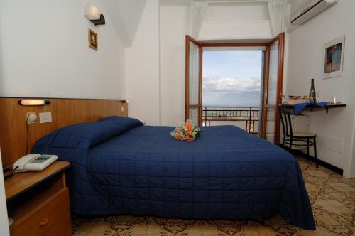 a bedroom with a bed with a blue blanket and a window at Hotel Crocenzi in San Marino