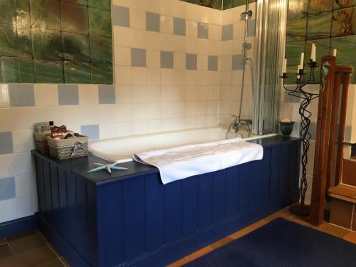 bagno con vasca blu e lavandino di Les Rivieres a Caumont-sur-Orne